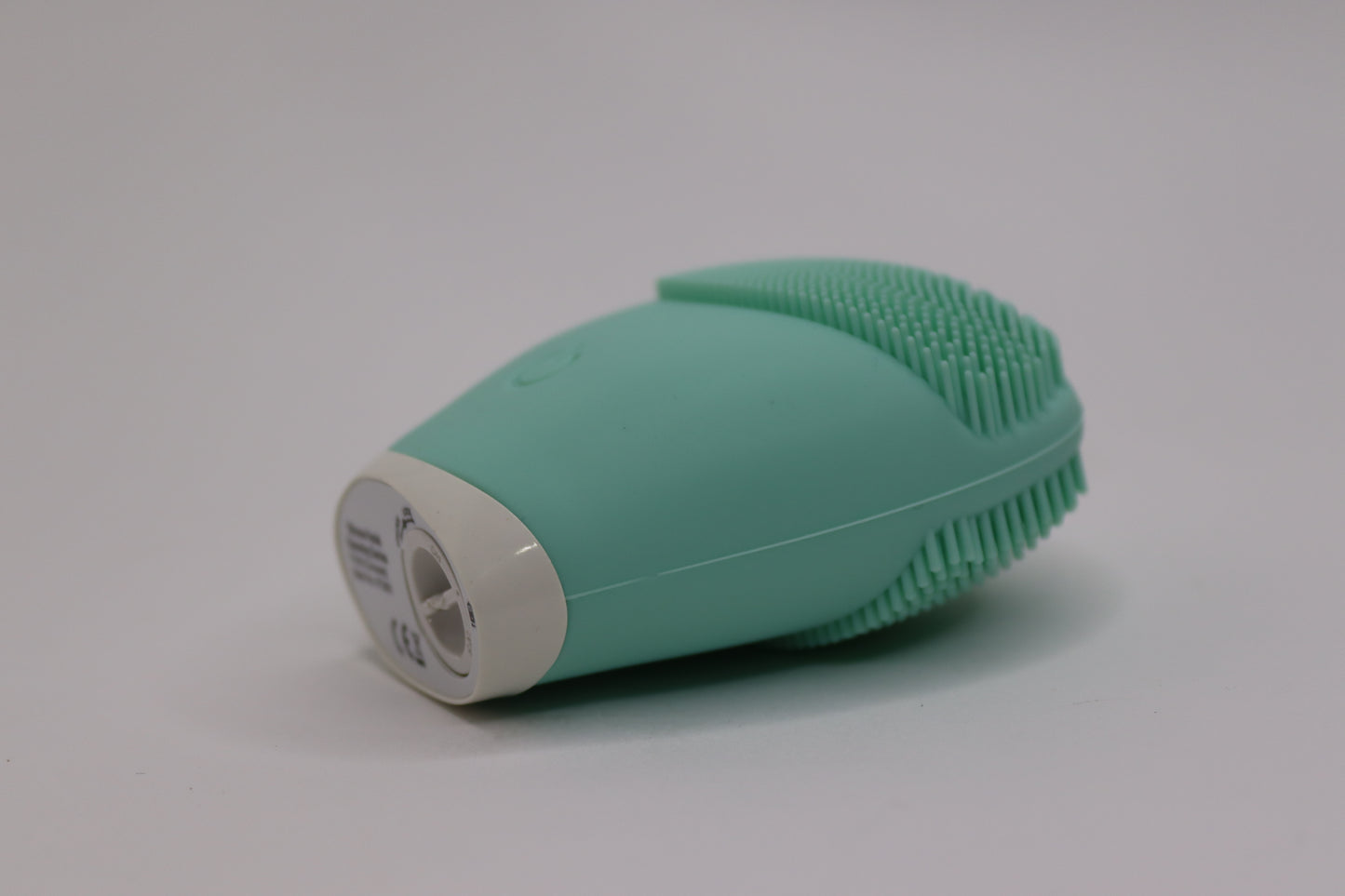 A rechargeable green silicone facial cleansing brush with soft bristles and a power button, designed for deep cleansing and gentle exfoliation, featuring a waterproof body and ergonomic shape.