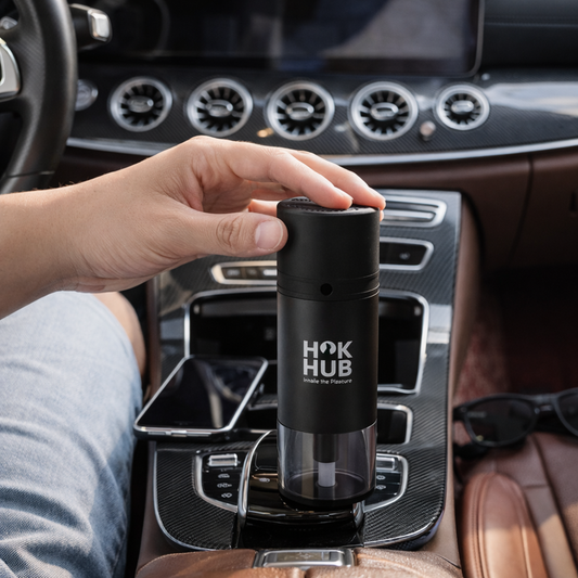 Hook Hub black portable device placed in a luxury car interior with a hand touching the top for size and lifestyle context.