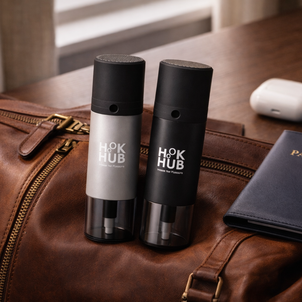 Hook Hub black and silver portable devices placed on a leather travel bag next to a passport holder.