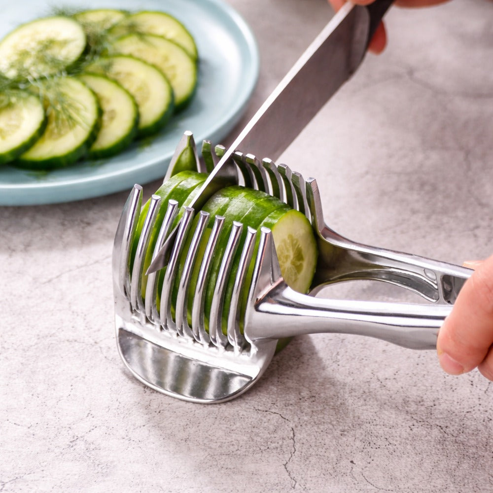 A stainless-steel food slicer holding a cucumber while slicing, with a blue plate of cucumber slices visible in the background.